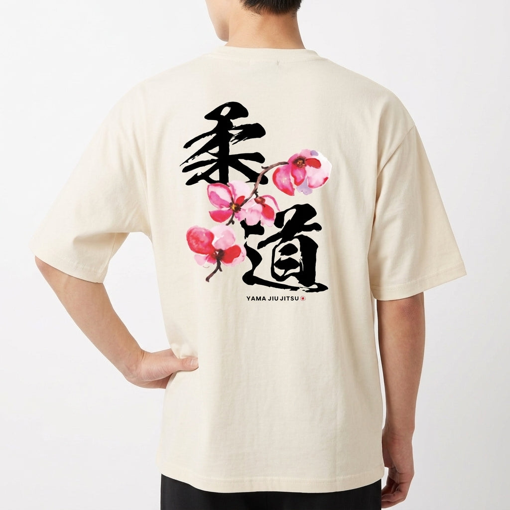 Camiseta com estampa frontal de texto "YAMA JIU JITSU" em letras pequenas e estampa traseira de caracteres japoneses grandes com flores estilizadas.