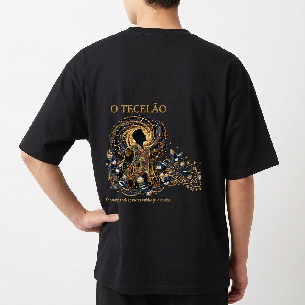 Camiseta com estampa frontal de design intrincado com elementos florais ao redor de texto e estampa traseira de figura mística centralizada com ornamentos detalhados.