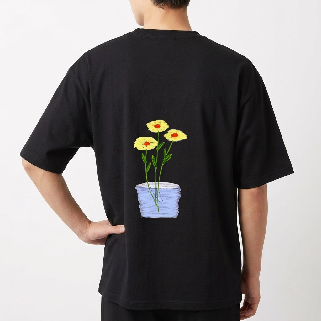 Camiseta com estampa frontal de texto em letras simples "Il raccolto è inevitabile." e estampa traseira de vaso azul com três flores amarelas e caule verde.