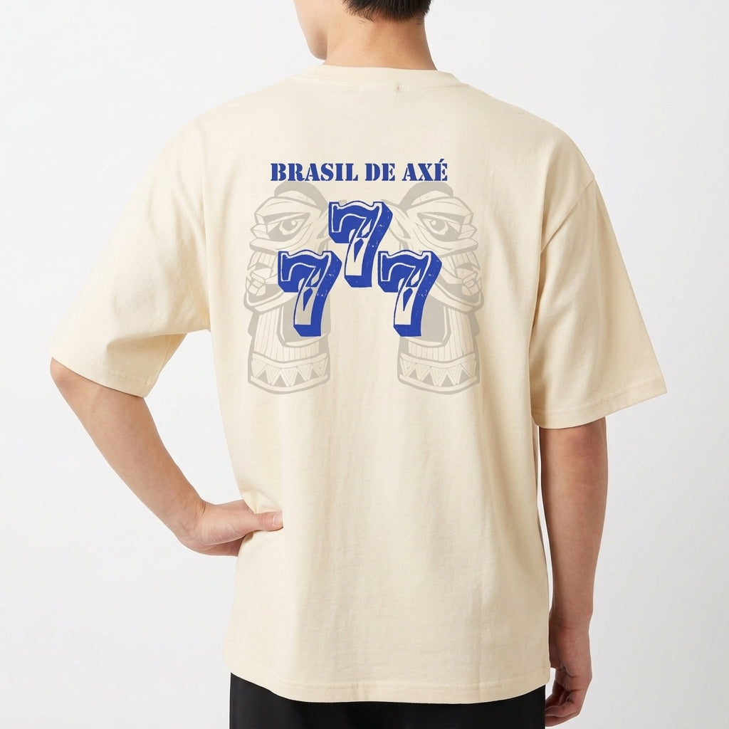 Camiseta com estampa frontal de brasão estilizado e estampa traseira de rosto tribal com "Brasil de Axé" acima e o número "777" em destaque.