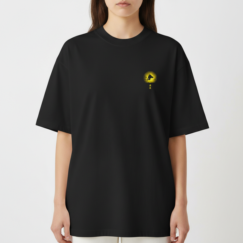 Camiseta com estampa frontal de símbolo circular com silhueta e estampa traseira de figura dinâmica em frente a um disco grande e um busto pequeno.