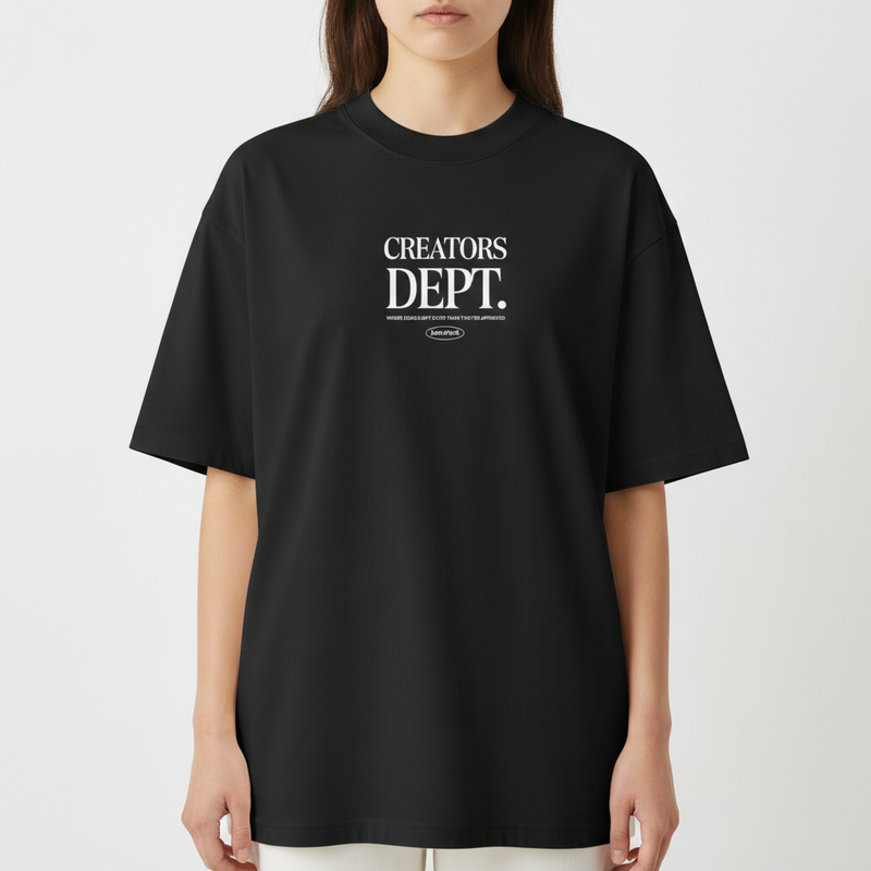 Camiseta com estampa frontal de texto "CREATORS DEPT." em destaque, acompanhada por uma frase menor e logo oval discretamente posicionada abaixo.
