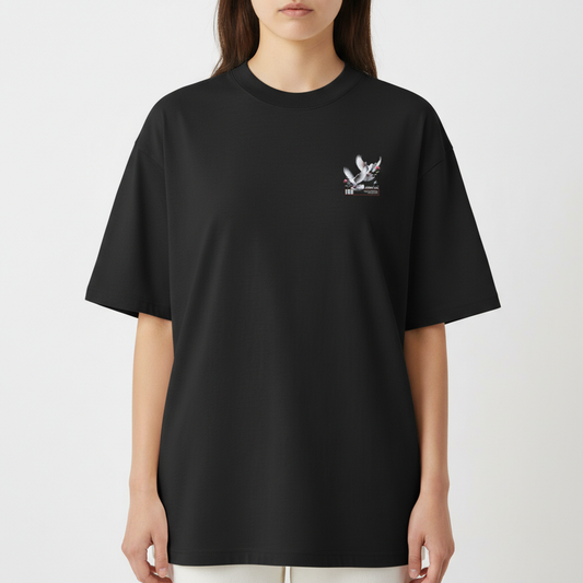 Camiseta com estampa frontal de uma pomba sutilmente detalhada, acompanhada por pequenas flores e elementos gráficos, ao lado de formas geométricas urbanas.