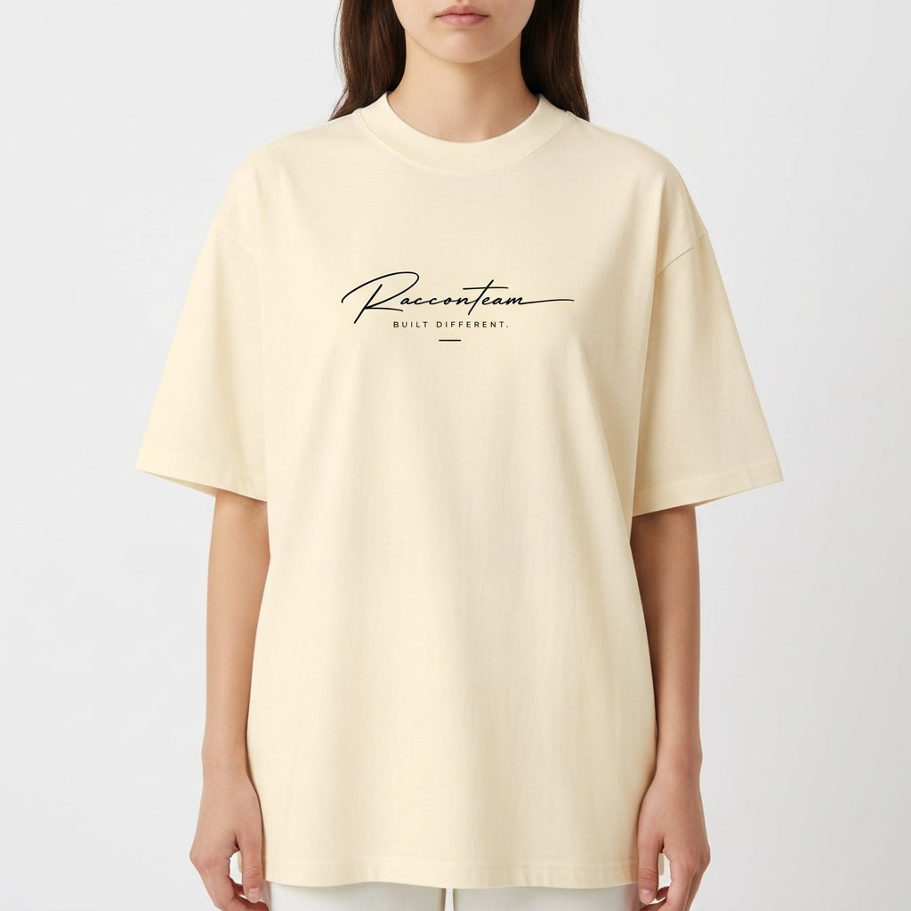 Camiseta com estampa frontal de lettering cursivo "Racoon Team - Built Different" e estampa traseira de iniciais grandes "RT", texto "Raccon Team - Est. 2017".