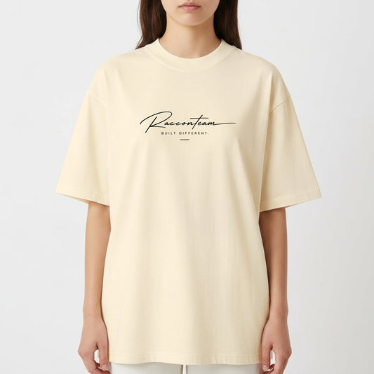 Camiseta com estampa frontal de lettering cursivo "Racoon Team - Built Different" e estampa traseira de iniciais grandes "RT", texto "Raccon Team - Est. 2017".