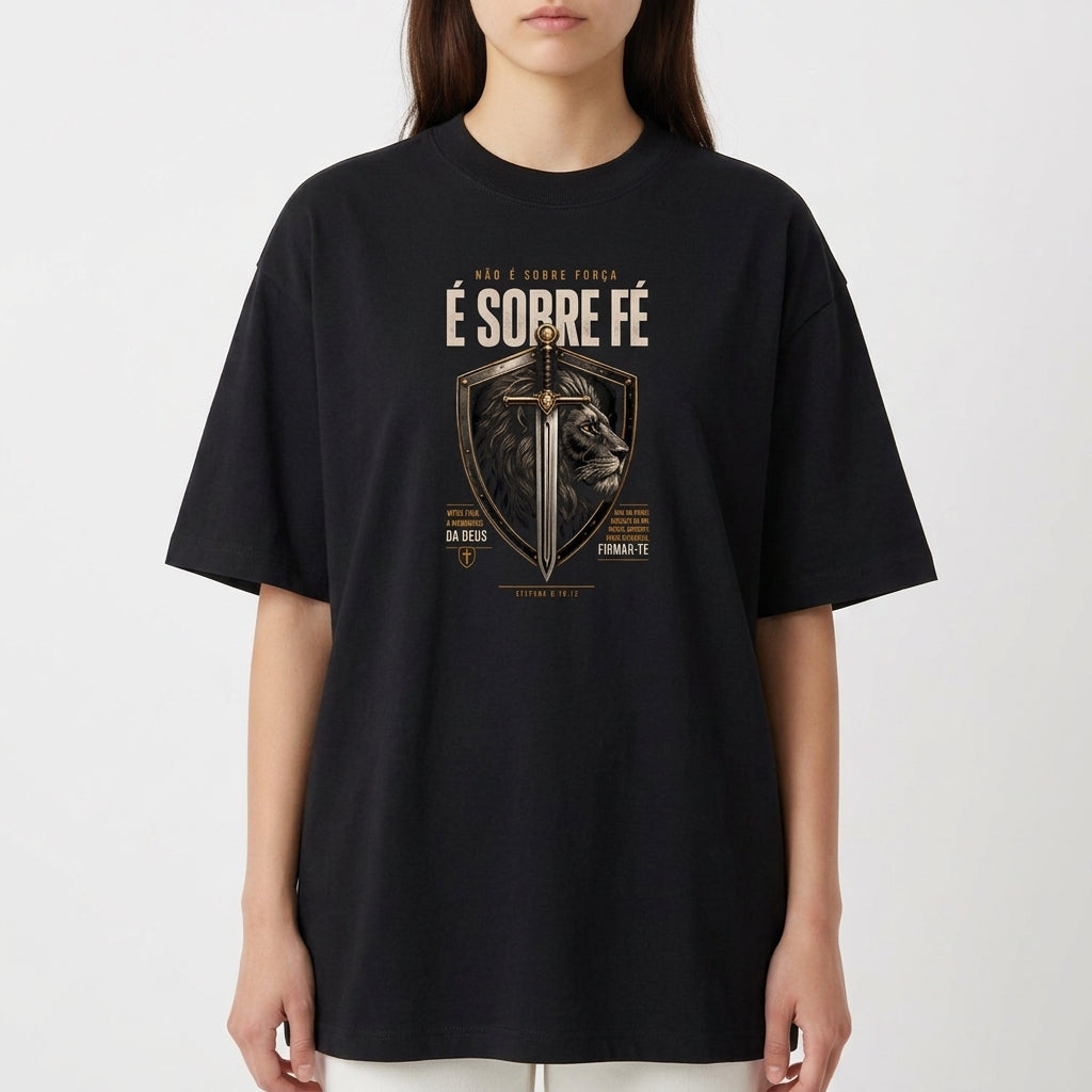 Camiseta com estampa frontal de escudo contendo uma espada centralizada e a imagem de um leão ao fundo, com textos ao redor enfatizando fé.