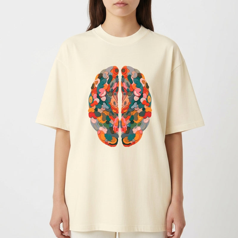 Camiseta com estampa frontal de um cérebro estilizado composto por formas semicirculares, sobrepostas em padrão complexo de tons variados.