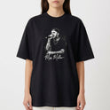 Camiseta com estampa frontal de um artista cantando no microfone, vestindo boné e camisa preta, destacando tatuagens nos braços e autógrafo abaixo.