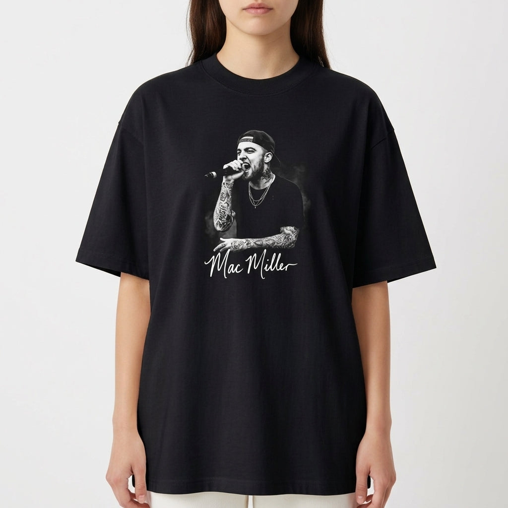 Camiseta com estampa frontal de um artista cantando no microfone, vestindo boné e camisa preta, destacando tatuagens nos braços e autógrafo abaixo.