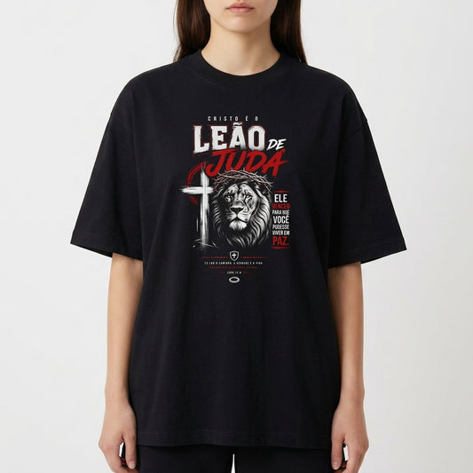 Camiseta com estampa frontal de um leão estilizado ao lado de uma cruz, acompanhada por textos destacados em diferentes tamanhos e fontes expressivas.