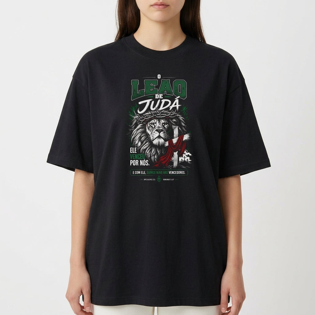 Camiseta com estampa frontal de leão com detalhes gráficos, textos destacando 'Leão de Judá' e frases adicionais em estilo tipográfico.