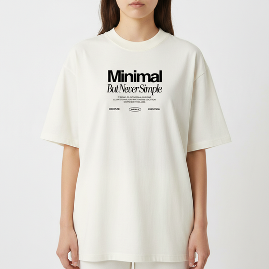 Camiseta com estampa frontal de texto destacando as palavras "Minimal But Never Simple", acompanhada de pequenos textos e símbolos abaixo.