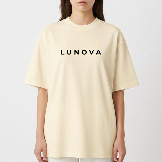 Camiseta com estampa frontal de texto estilizado "LUNOVA" em tipografia limpa e moderna e estampa traseira de anjo detalhado com asas amplas e a inscrição "FREEDOM AND PEACE".
