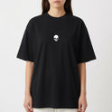 Camiseta com estampa frontal de caveira pequena e estampa traseira de pássaro em voo com texto estilizado por baixo, criando um contraste marcante.