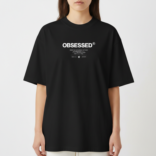 Camiseta com estampa frontal de texto grande "OBSESSED" e abaixo uma sequência de textos menores combinando palavras e símbolos minimalistas.