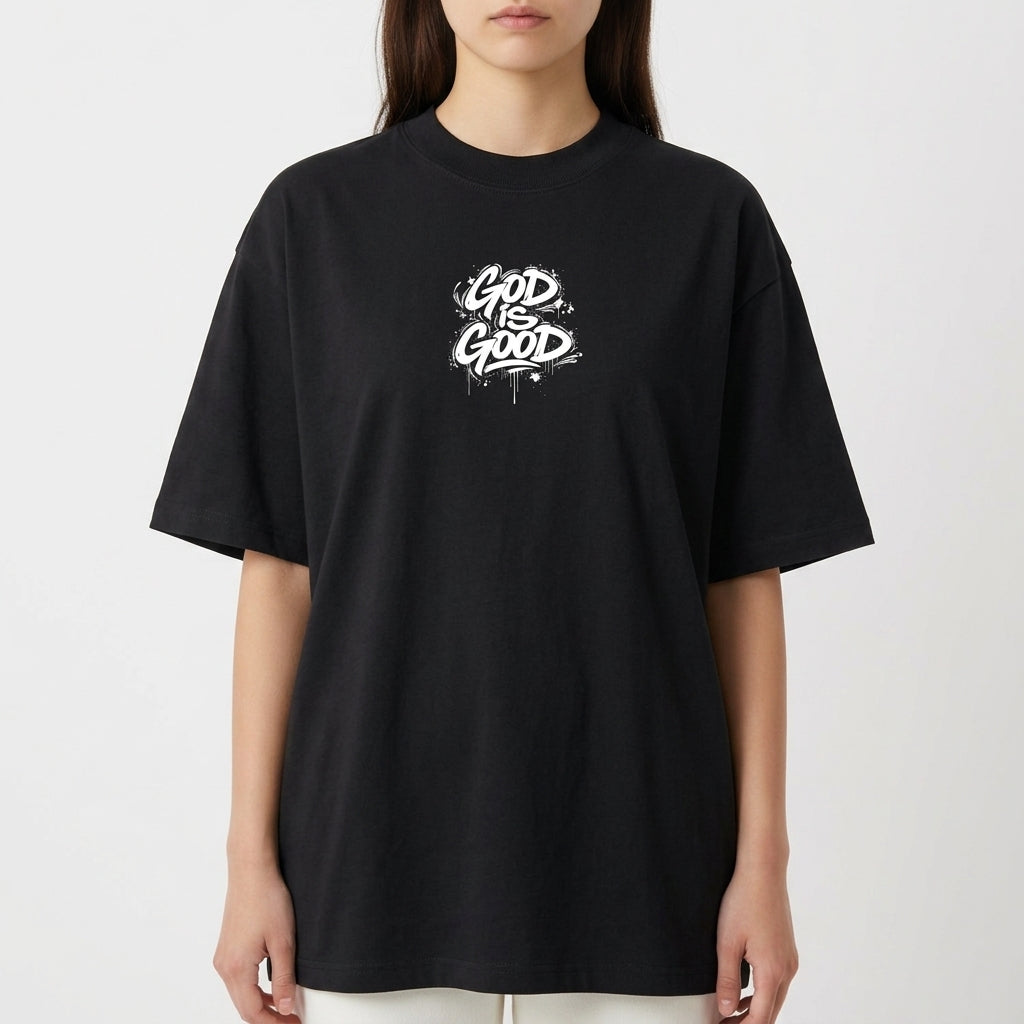 Camiseta com estampa frontal de lettering "God is Good" em estilo grafite e estampa traseira de crucifixo sobre a palavra "Jesus" e texto relacionado.