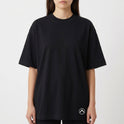 Camiseta com estampa frontal de símbolo minimalista no canto inferior e estampa traseira de paisagem praiana ao entardecer com padrão de calçada ondulada.