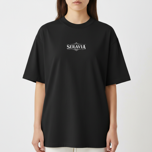 Camiseta com estampa frontal de "Seravia" em letras estilizadas e detalhe ornamental, e estampa traseira de Anúbis, o deus egípcio, com asas e tochas.