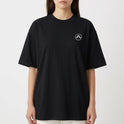 Camiseta com estampa frontal de símbolo minimalista e estampa traseira de fita cassete retro em cenário neon com palmeiras e pôr do sol vibrante.