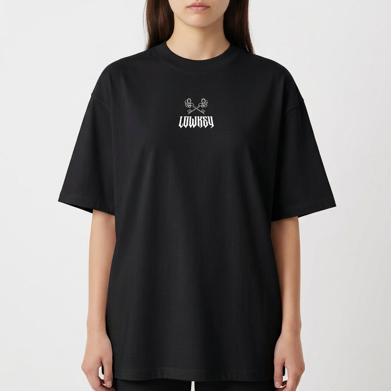 Camiseta com estampa frontal de duas caveiras cruzadas acima da palavra "LOWKEY" e estampa traseira da mesma palavra em estilo sombreado.
