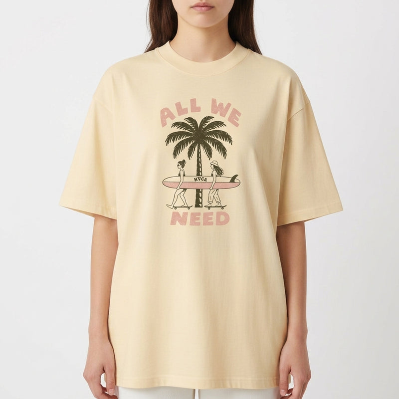Camiseta com estampa frontal de duas pessoas carregando uma prancha de surfe diante de um coqueiro, acompanhada pela frase "ALL WE NEED".
