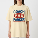 Camiseta com estampa frontal de texto estilizado com palavras "COACH PHD PARKER" em destaque, acompanhada de "PHILOSOPHY OF HEAVY DUTY" em menor tamanho.
