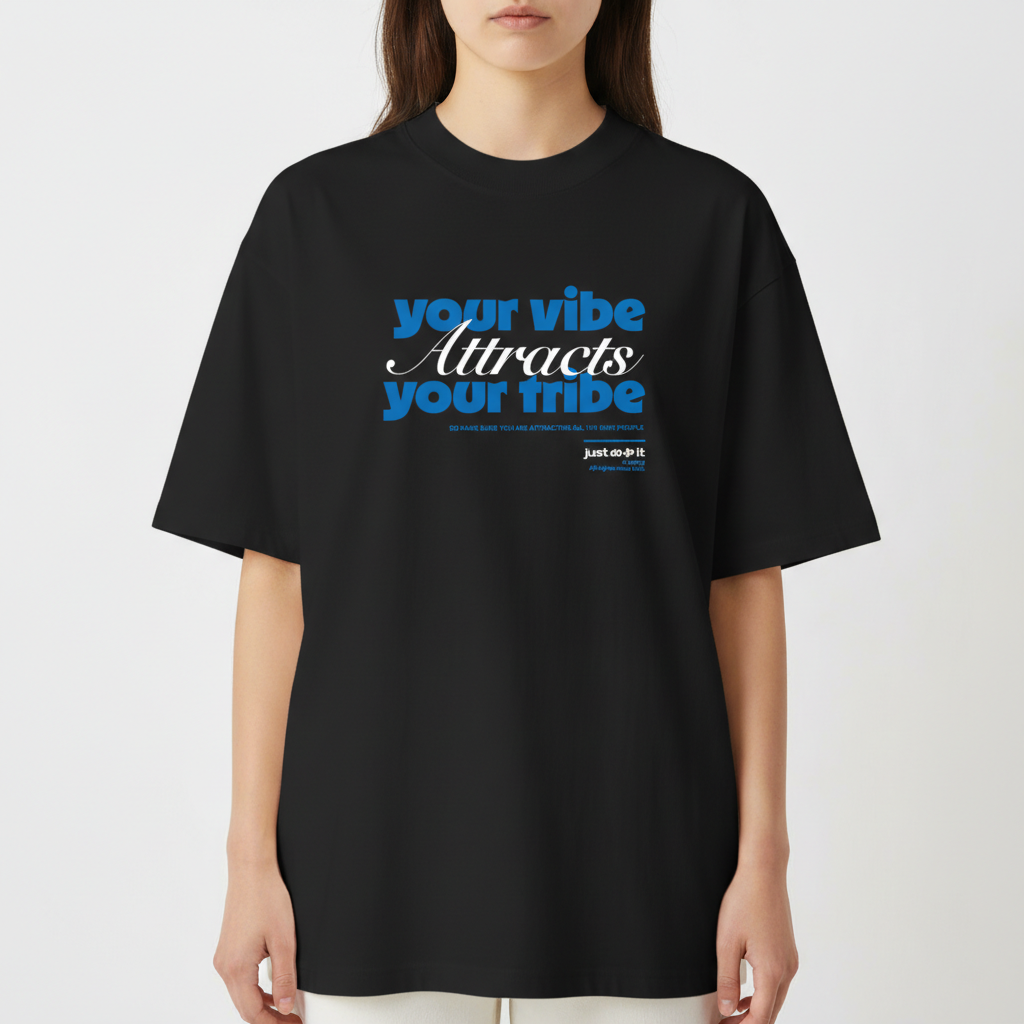 Camiseta com estampa frontal de texto estilizado "your vibe attracts your tribe" em letras grandes, acompanhada de pequenos detalhes textuais complementares.