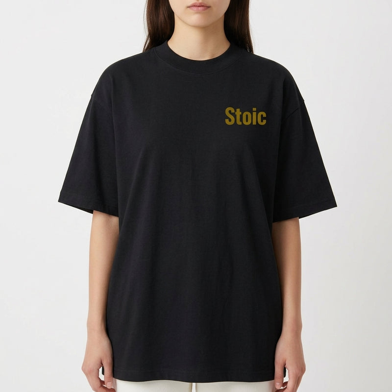 Camiseta com estampa frontal de "Stoic" no peito e estampa traseira com o texto "Love of One's Fate", acompanhada de parágrafo reflexivo e símbolos.