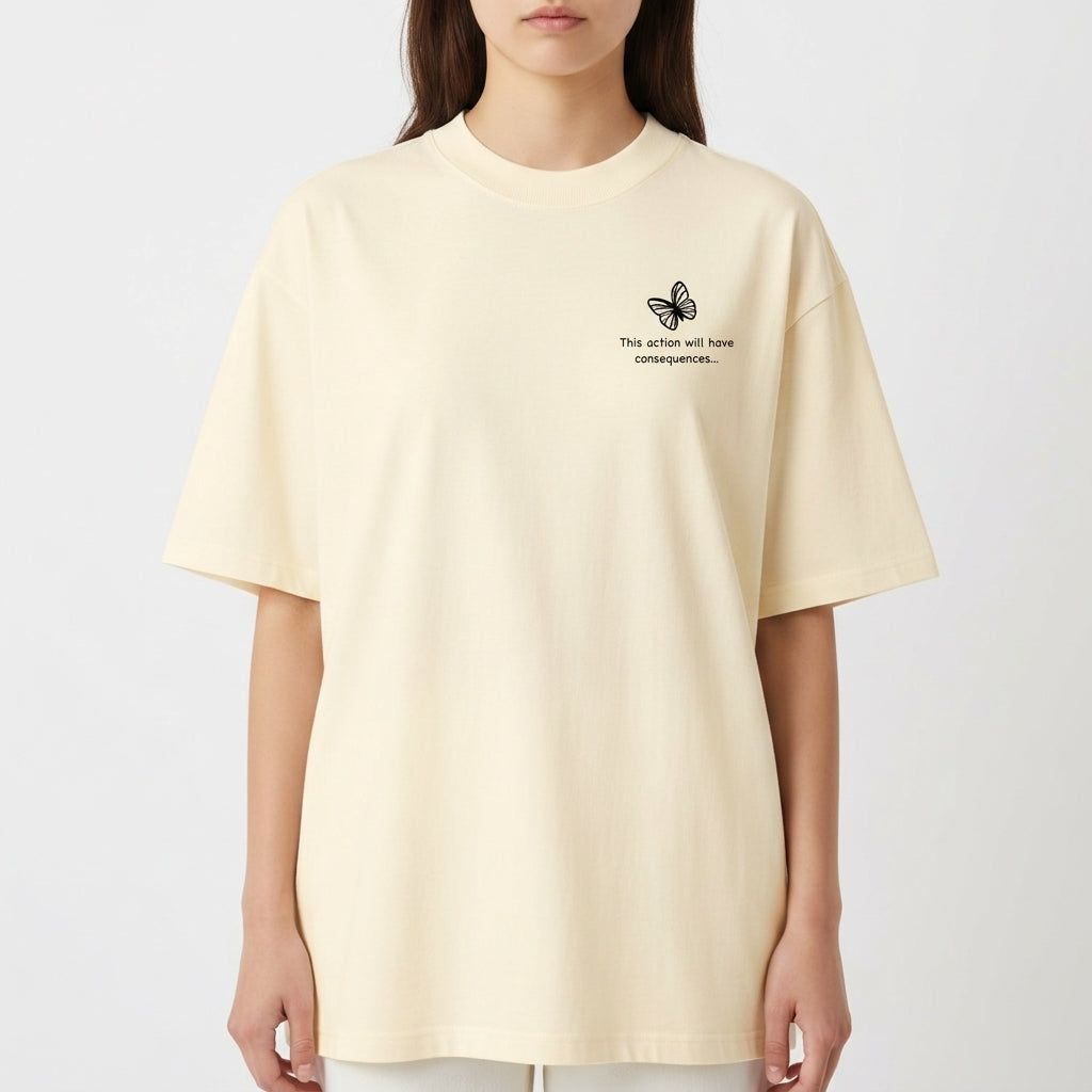 Camiseta com estampa frontal de borboleta pequena acompanhada da frase “This action will have consequences...” e estampa traseira de arte com personagem estilizada segurando uma arma, cercada por palavras e símbolos, incluindo "STRANGE" em destaque.
