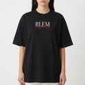 Camiseta com estampa frontal de letras estilizadas "RLEM" em branco, sobrepostas a uma assinatura cursiva na cor vermelha, criando um contraste marcante.