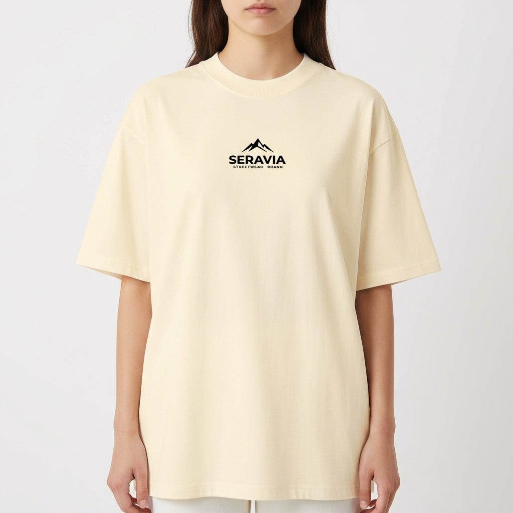Camiseta com estampa frontal de montanha e texto sob ela, e estampa traseira detalhada de figura mitológica central cercada por caveiras e chamas.