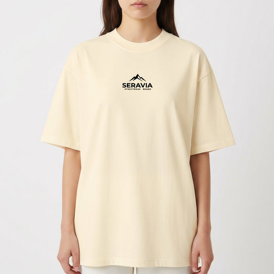 Camiseta com estampa frontal de montanha e texto sob ela, e estampa traseira detalhada de figura mitológica central cercada por caveiras e chamas.