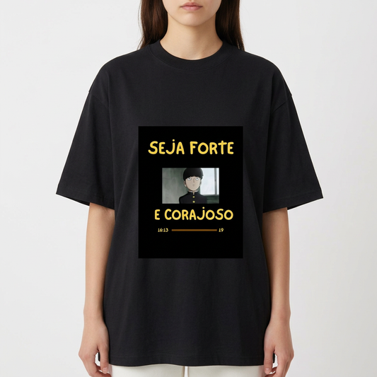 Camiseta com estampa frontal de personagem de cabelo curto em estilo desenho animado com mensagem inspiradora "SEJA FORTE E CORAJOSO" em letras destacadas.