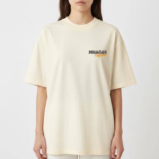 Camiseta com estampa frontal de texto "MIRACLES I BELIEVE" em fonte estilizada e traseira de texto "NUNCA VIMOS NADA IGUAL" com variação de cores e tamanhos.
