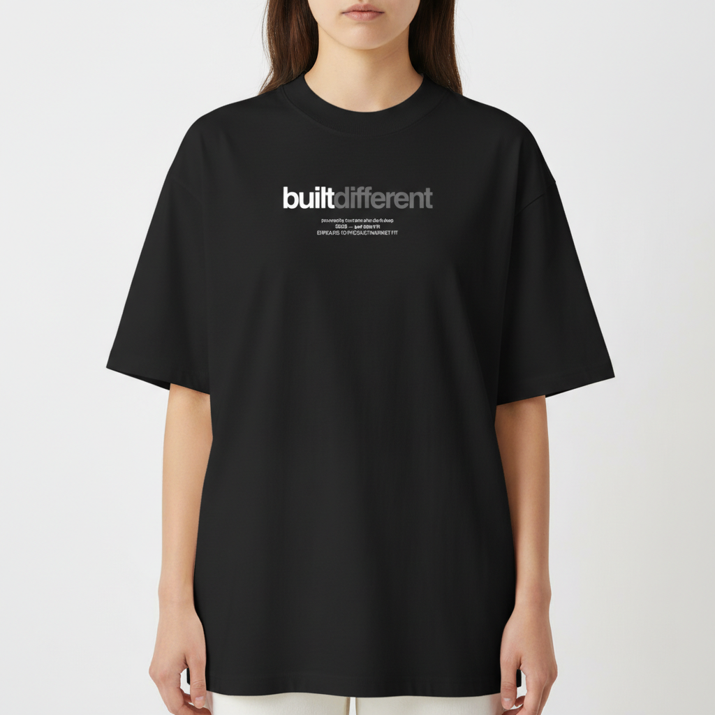 Camiseta com estampa frontal de texto "built different" em destaque, acompanhado por linhas menores com frases adicionais, em um estilo moderno e impactante.