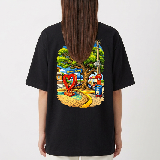 Camiseta com estampa frontal de "PITANGUI" sublinhado e estampa traseira de uma praça com árvore central, banco de madeira e placa de "PAZ E AMOR".