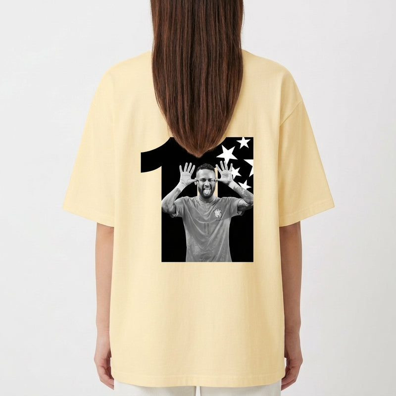Camiseta com estampa traseira de uma figura dentro do número onze, acompanhada de um fundo repleto de estrelas em um formato dinâmico.