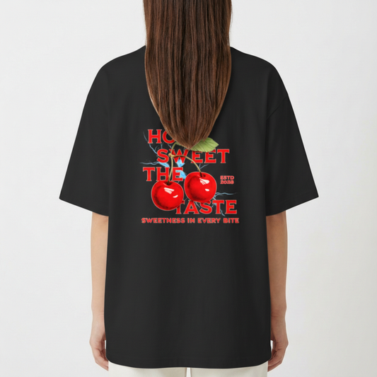 Camiseta com estampa traseira de cerejas reluzentes, folhas verdejantes e destaque para os dizeres "HOW SWEET THE TASTE" e "SWEETNESS IN EVERY BITE".