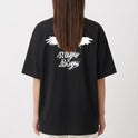 Camiseta com estampa frontal de caveira pequena e estampa traseira de pássaro em voo com texto estilizado por baixo, criando um contraste marcante.
