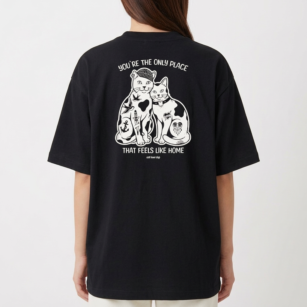 Camiseta com estampa frontal de duas cabeças de gatos em estilo ilustrativo e estampa traseira de dois gatos sentados rodeados por detalhes artísticos.