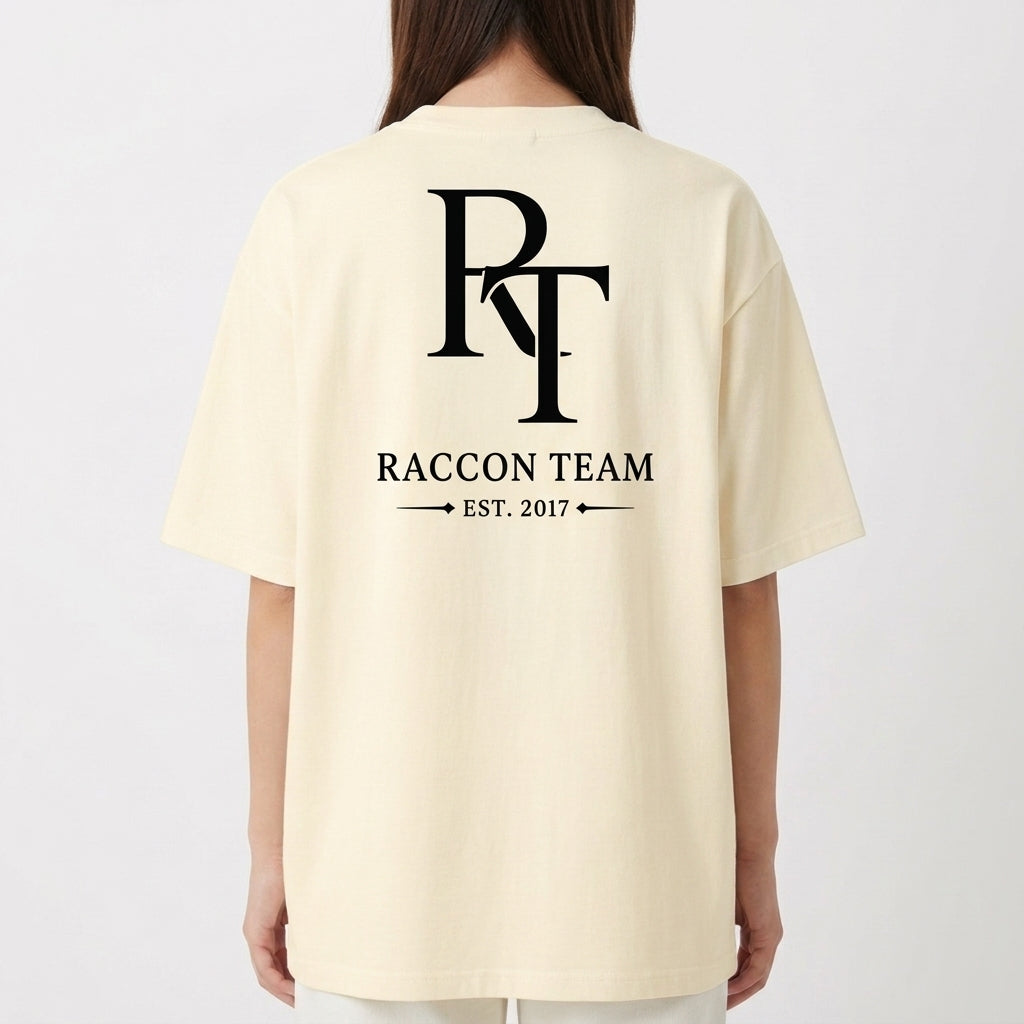Camiseta com estampa frontal de lettering cursivo "Racoon Team - Built Different" e estampa traseira de iniciais grandes "RT", texto "Raccon Team - Est. 2017".