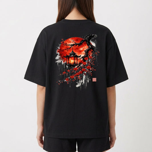 Camiseta com estampa frontal de texto "LUNOVA" com símbolo acima e estampa traseira de lanterna japonesa sob árvore de cerejeira com lua vermelha ao fundo.