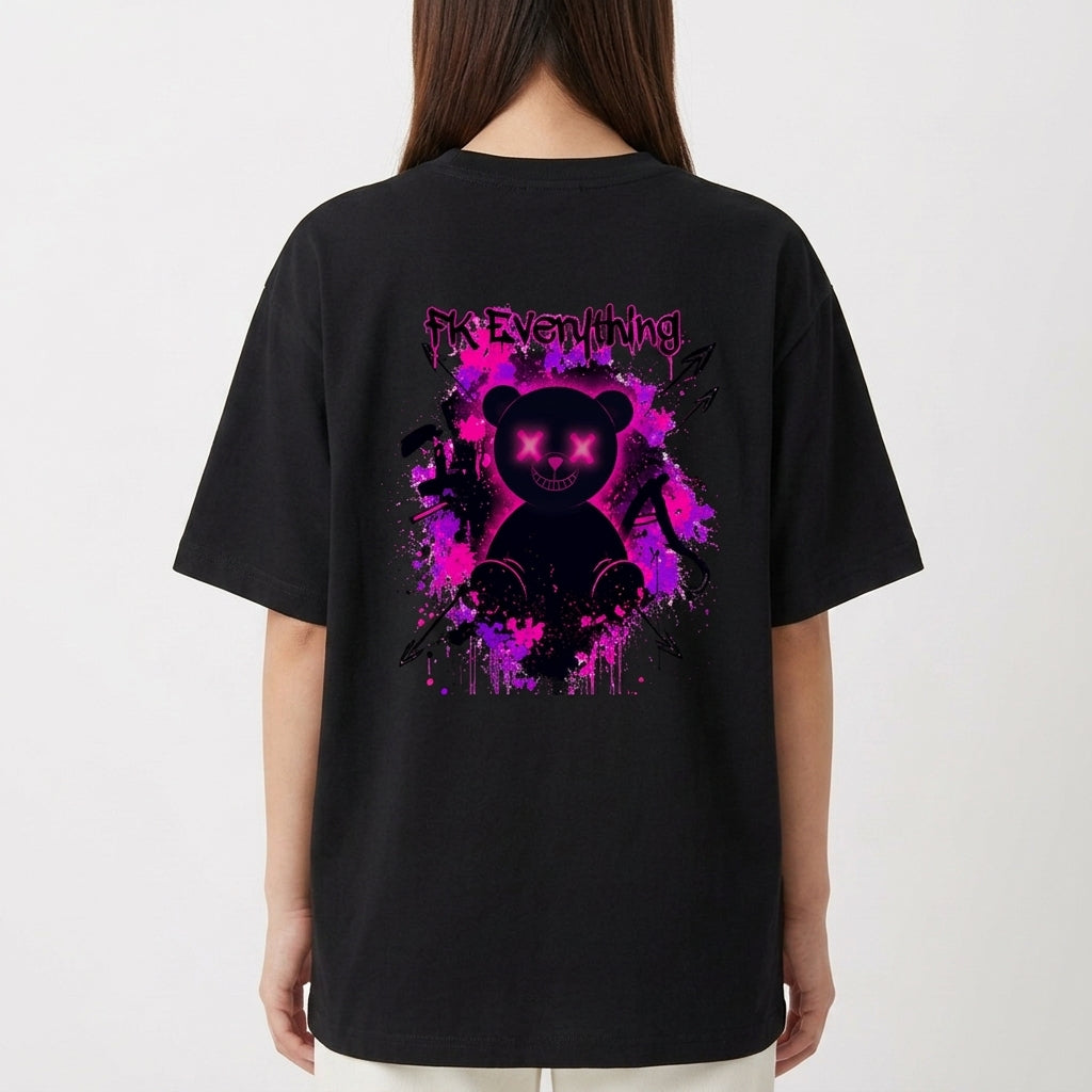 Camiseta com estampa frontal de inscrição estilizada e estampa traseira de urso sorridente com olhos em forma de "X" sobre fundo de respingos vibrantes.