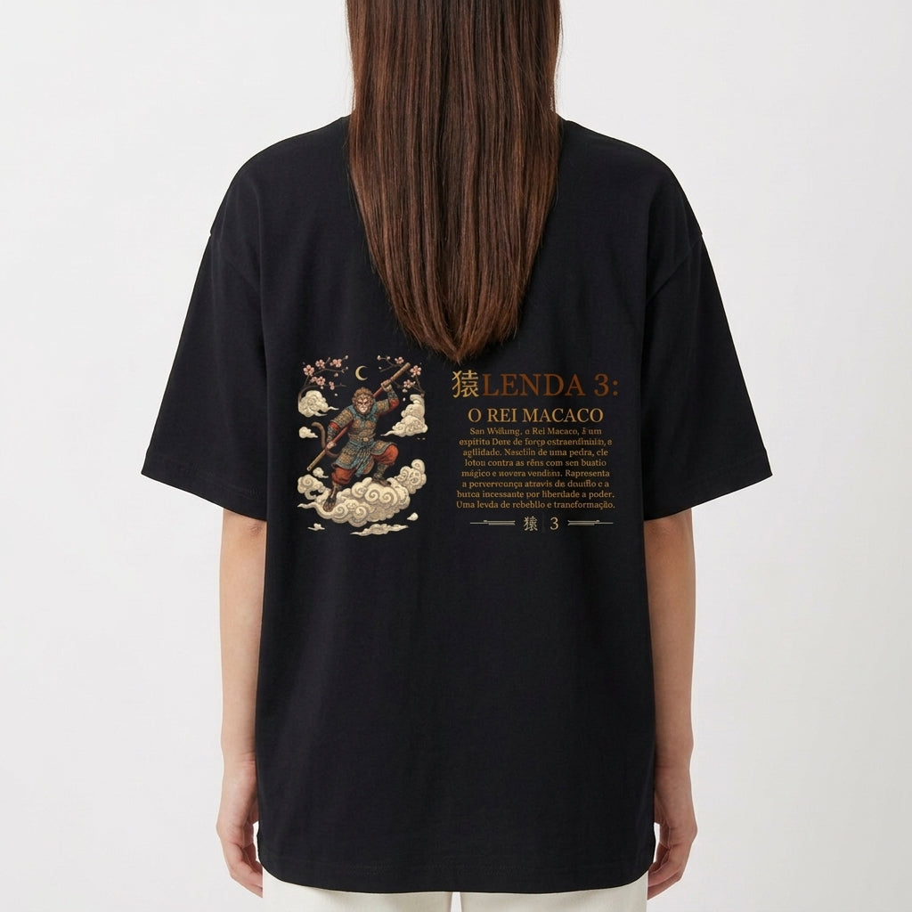 Camiseta com estampa frontal de um emblema dourado com uma coroa, texto "O Rei Macaco (Sun Wukong)" e estampa traseira de uma ilustração detalhada com "Lenda 3: O Rei Macaco".