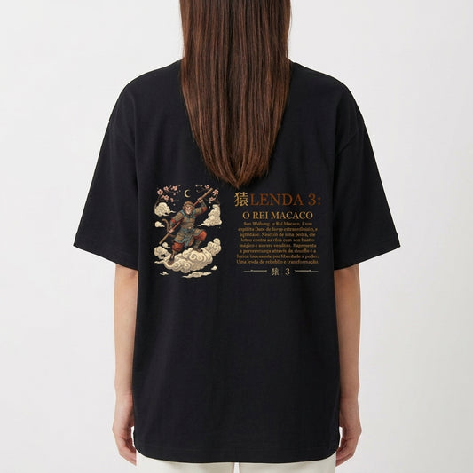 Camiseta com estampa frontal de um emblema dourado com uma coroa, texto "O Rei Macaco (Sun Wukong)" e estampa traseira de uma ilustração detalhada com "Lenda 3: O Rei Macaco".