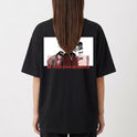 Camiseta com estampa frontal de texto em estilo grafite e estampa traseira de grupo fotográfico sobreposto a texto repetido "BE YOUR OWN REFERENCE".