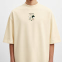 Camiseta com estampa frontal de dois rostos de perfil acompanhados de texto e estampa traseira de dois personagens em ação com elementos gráficos e texto.