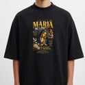 Camiseta com estampa frontal de figura religiosa, com detalhes de texto estilizado e elementos decorativos ao redor de uma imagem central.