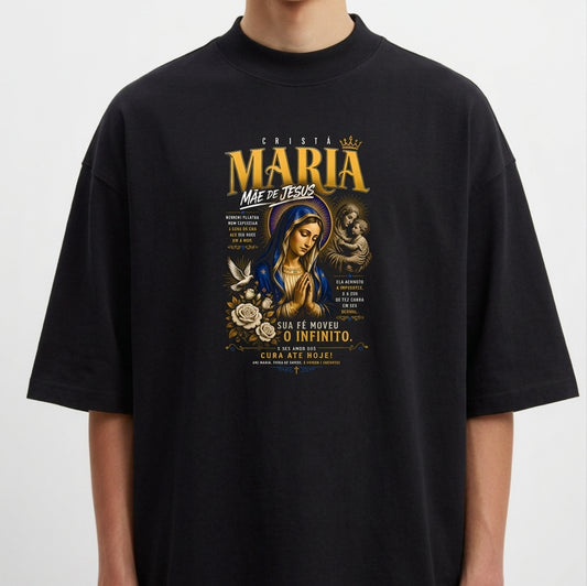 Camiseta com estampa frontal de figura religiosa, com detalhes de texto estilizado e elementos decorativos ao redor de uma imagem central.