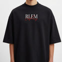 Camiseta com estampa frontal de letras estilizadas "RLEM" em branco, sobrepostas a uma assinatura cursiva na cor vermelha, criando um contraste marcante.
